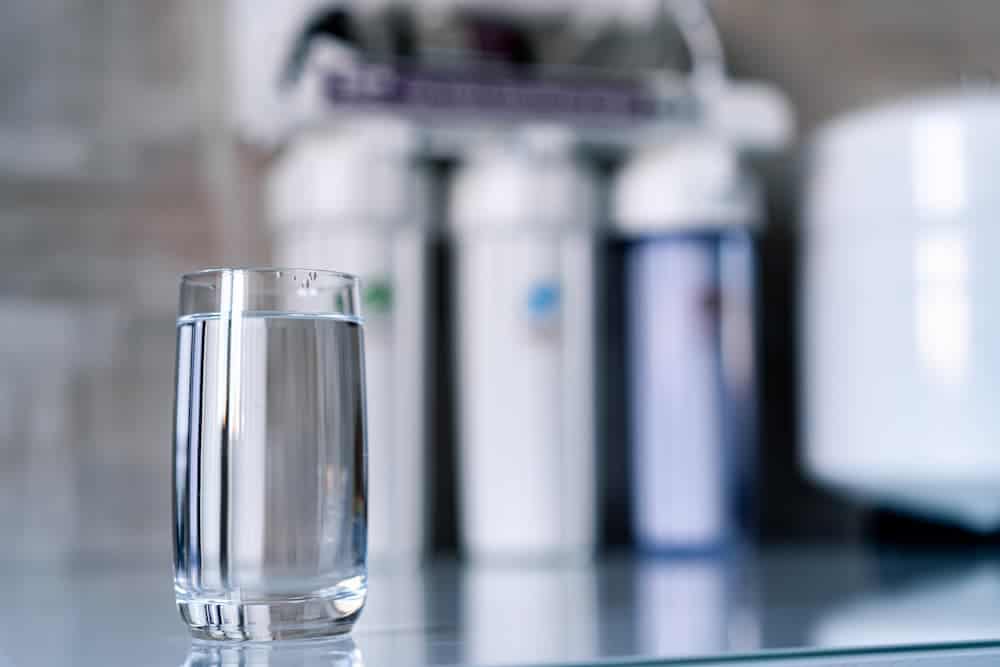 A glass of water in front of a water filtration system